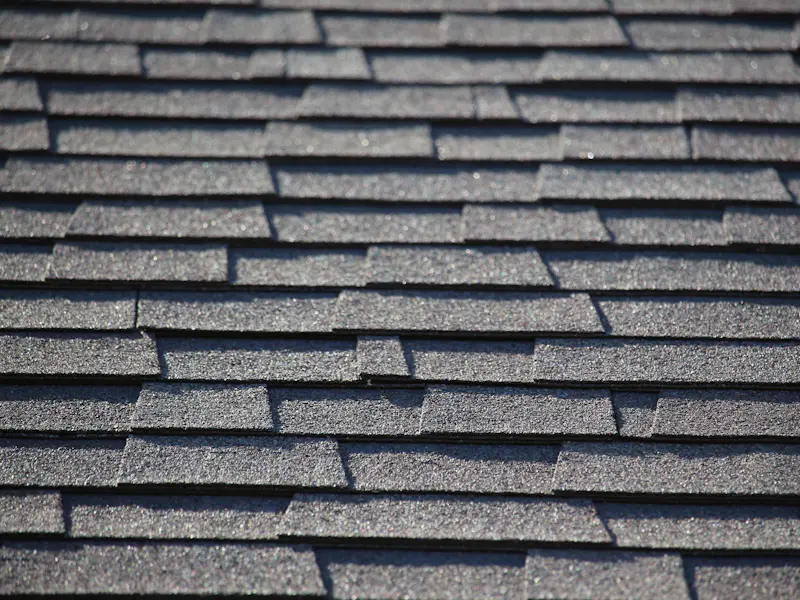 Architectural asphalt shingles in close-up showing granule texture and staggered reveal
