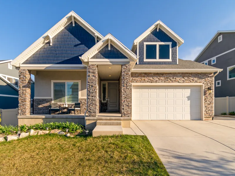 Blue-gray craftsman home with stacked gables, gray architectural shingles, and a standing-seam porch roof