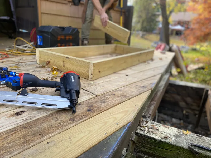 Framing nailer resting on fresh lumber during a roof deck rebuild — representative