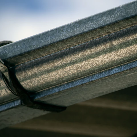 Metal gutter and bracket in close-up at the roof edge &mdash; representative