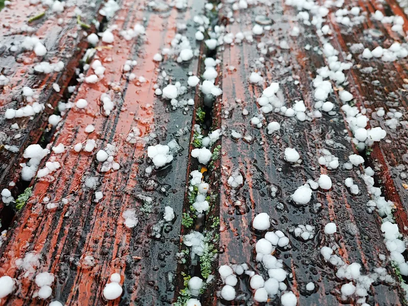 Hailstones scattered on wet wood after a storm — representative