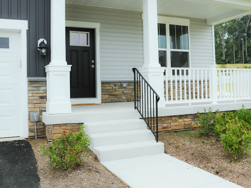 Navy and white farmhouse entry with covered porch, board-and-batten siding, and stone skirt