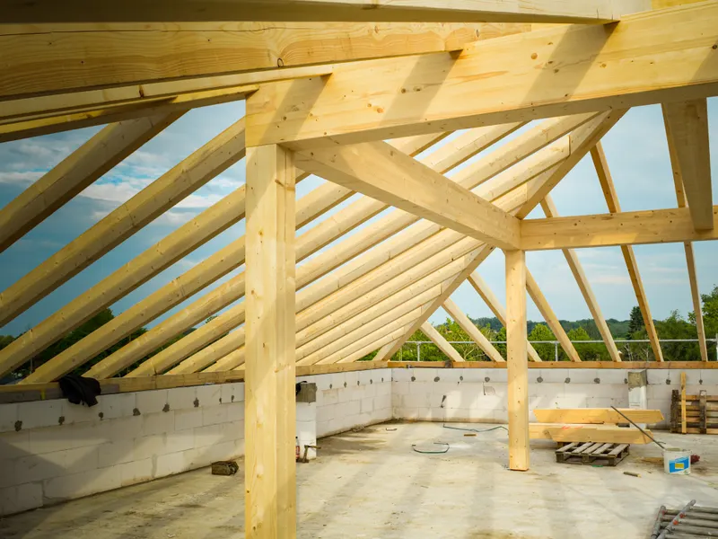 New rafter framing running to the ridge on an open roof build, sky visible between members