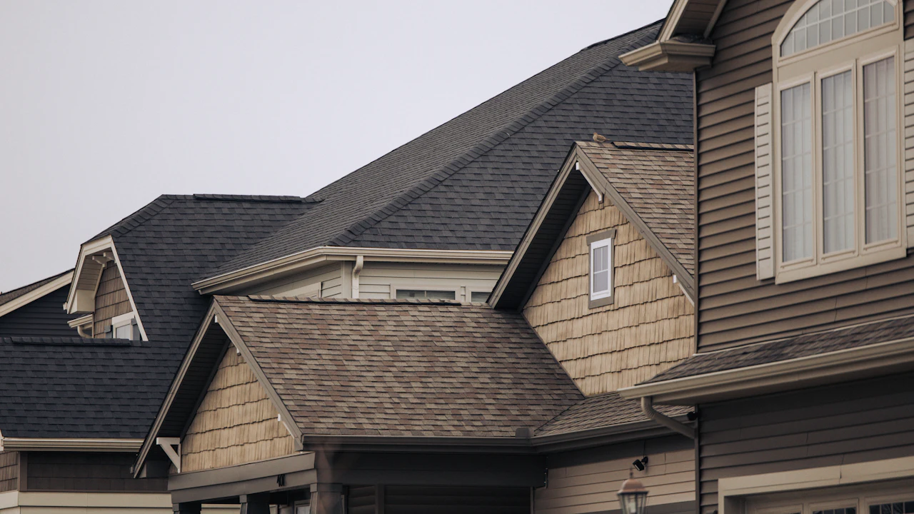 Intersecting gables and valleys of dark architectural shingle roofs on suburban homes