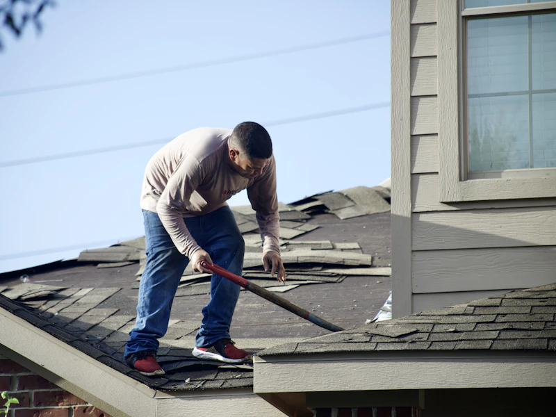 Old shingles being stripped to the deck during tear-off — representative