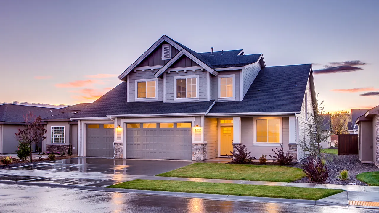 Two-story suburban home with steep architectural shingle roof at dusk — representative