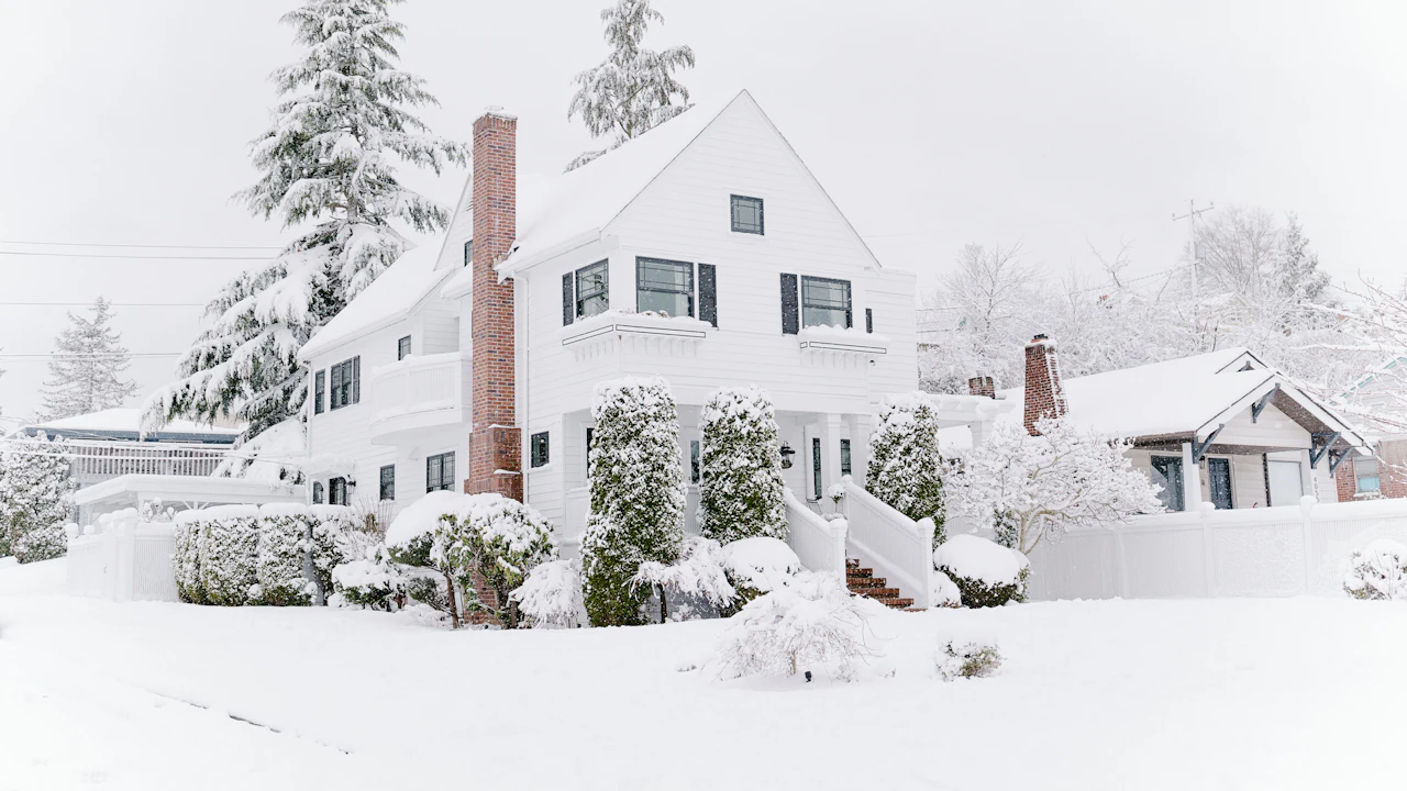 White colonial home and evergreens buried in deep snow after a lake-effect storm